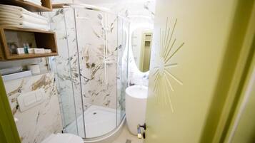 Un baño con ducha de vidrio, inodoro y lavabo.