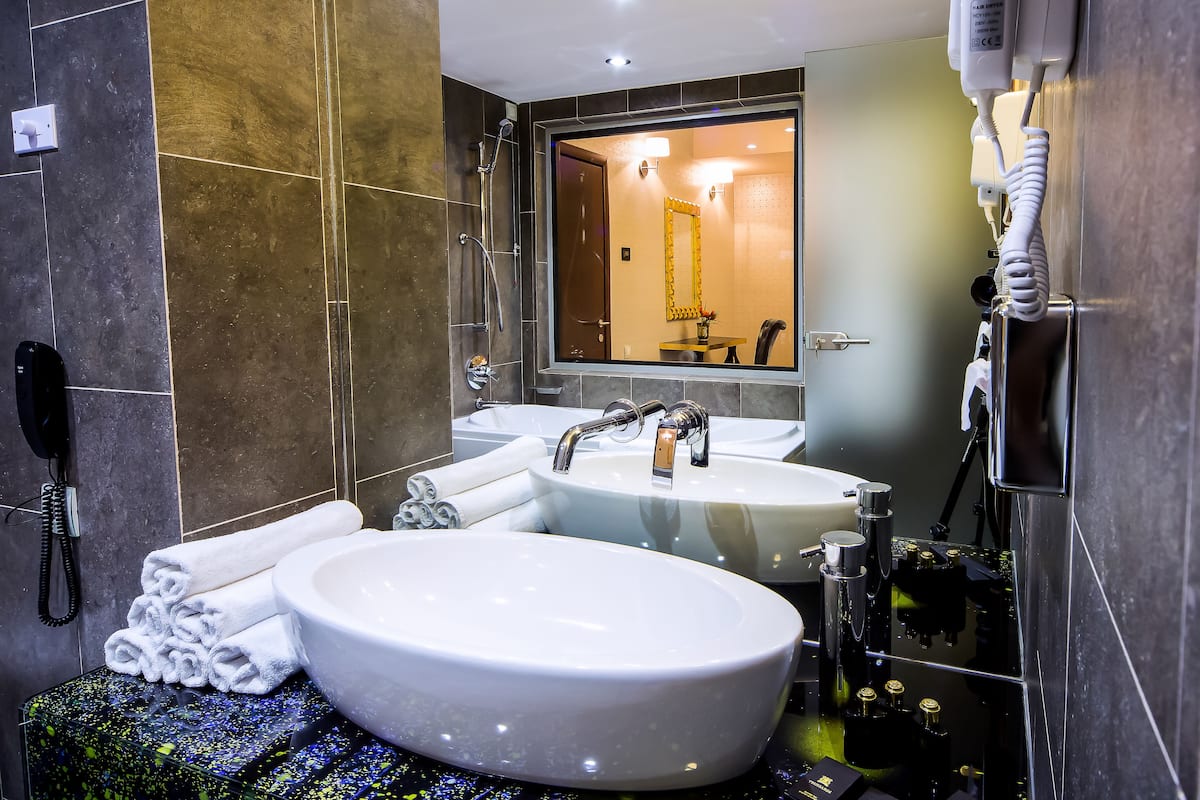 A modern bathroom with two sinks, a hairdryer, and a phone.
