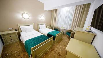 Habitación de hotel con dos camas, un escritorio, una silla, una mesita y un espejo.