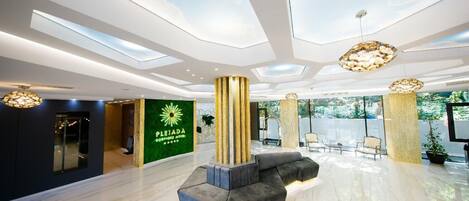A modern lobby with a reception desk, seating area, and a green wall with a logo.