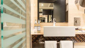 A modern bathroom with a large mirror, a sink, and two towels.
