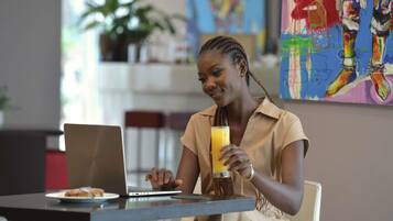 A person sitting at a table with a laptop and a glass of orange juice.