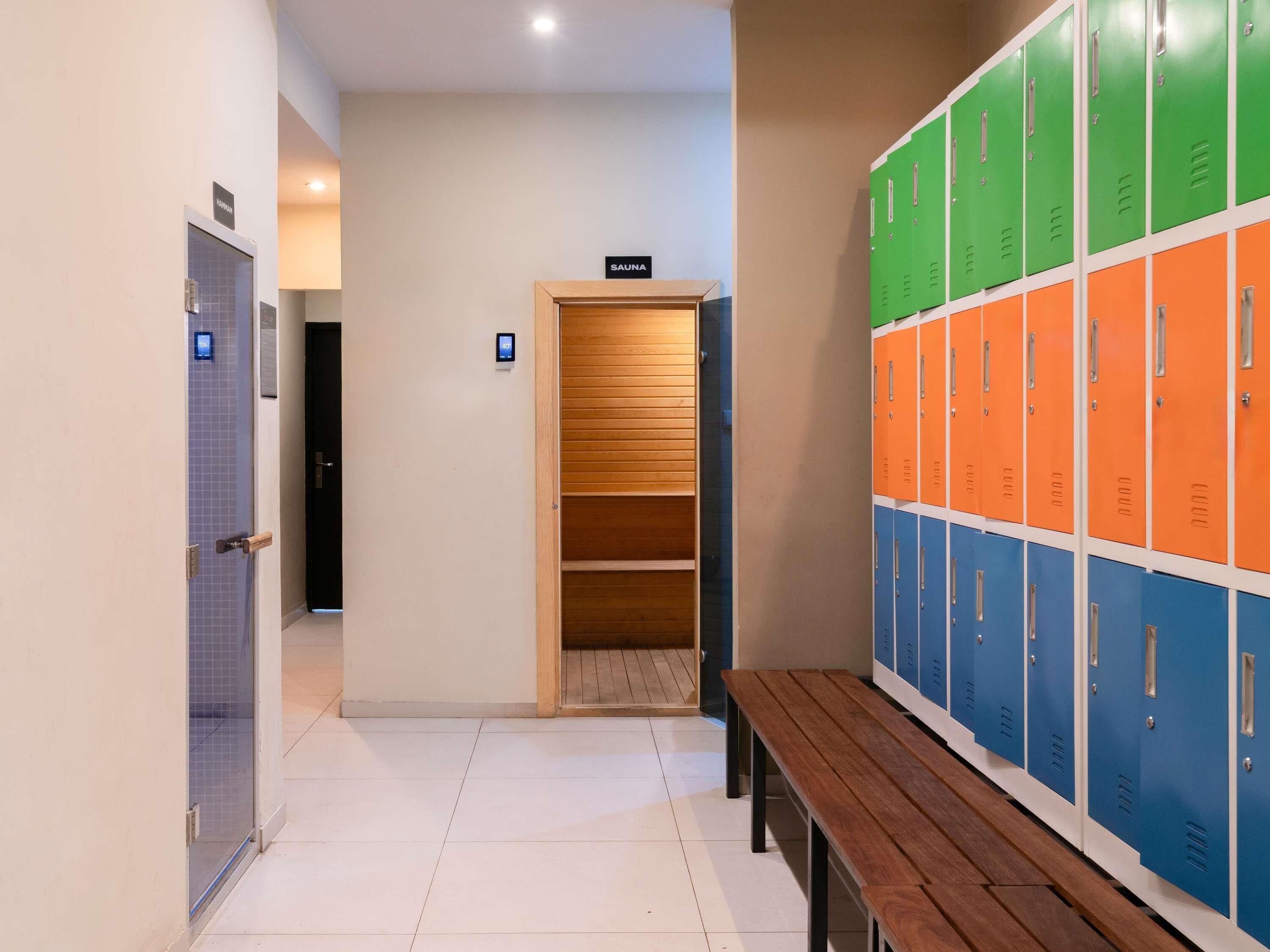 A hallway with lockers, a bench, and a sauna sign.