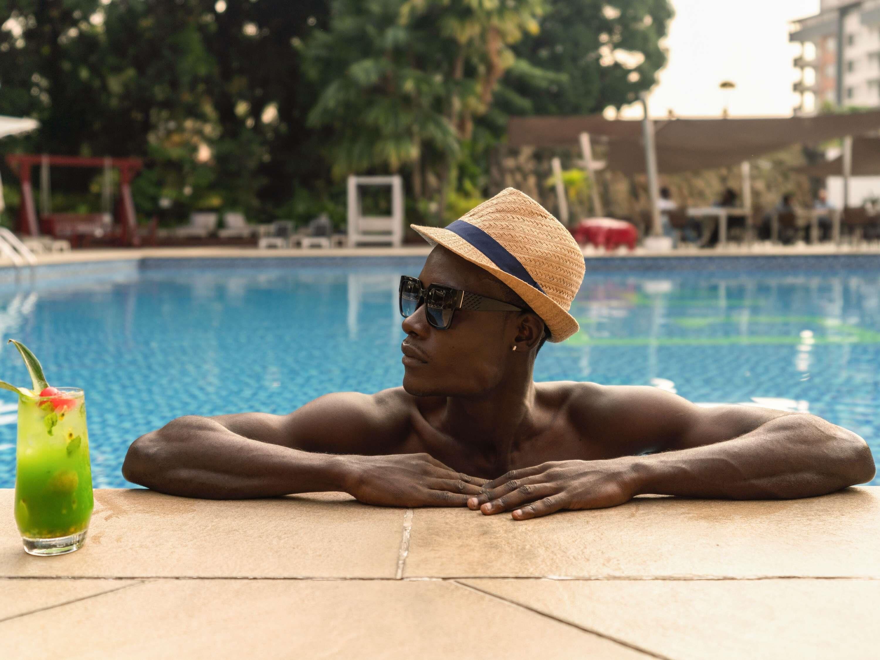 A person relaxing by a pool with a drink beside them.