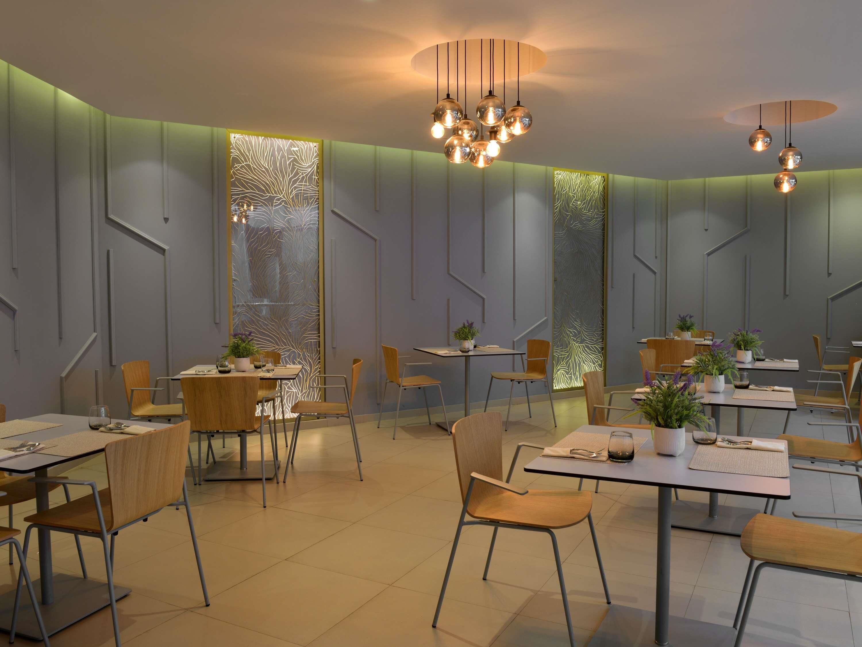 A modern dining area with tables, chairs, and decorative plants.