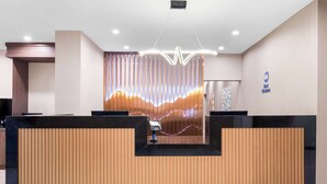 A reception area with a wooden reception desk, a modern light fixture, and a wall-mounted sign. - Best Western Niantic - New London/Mystic Area (Niantic)