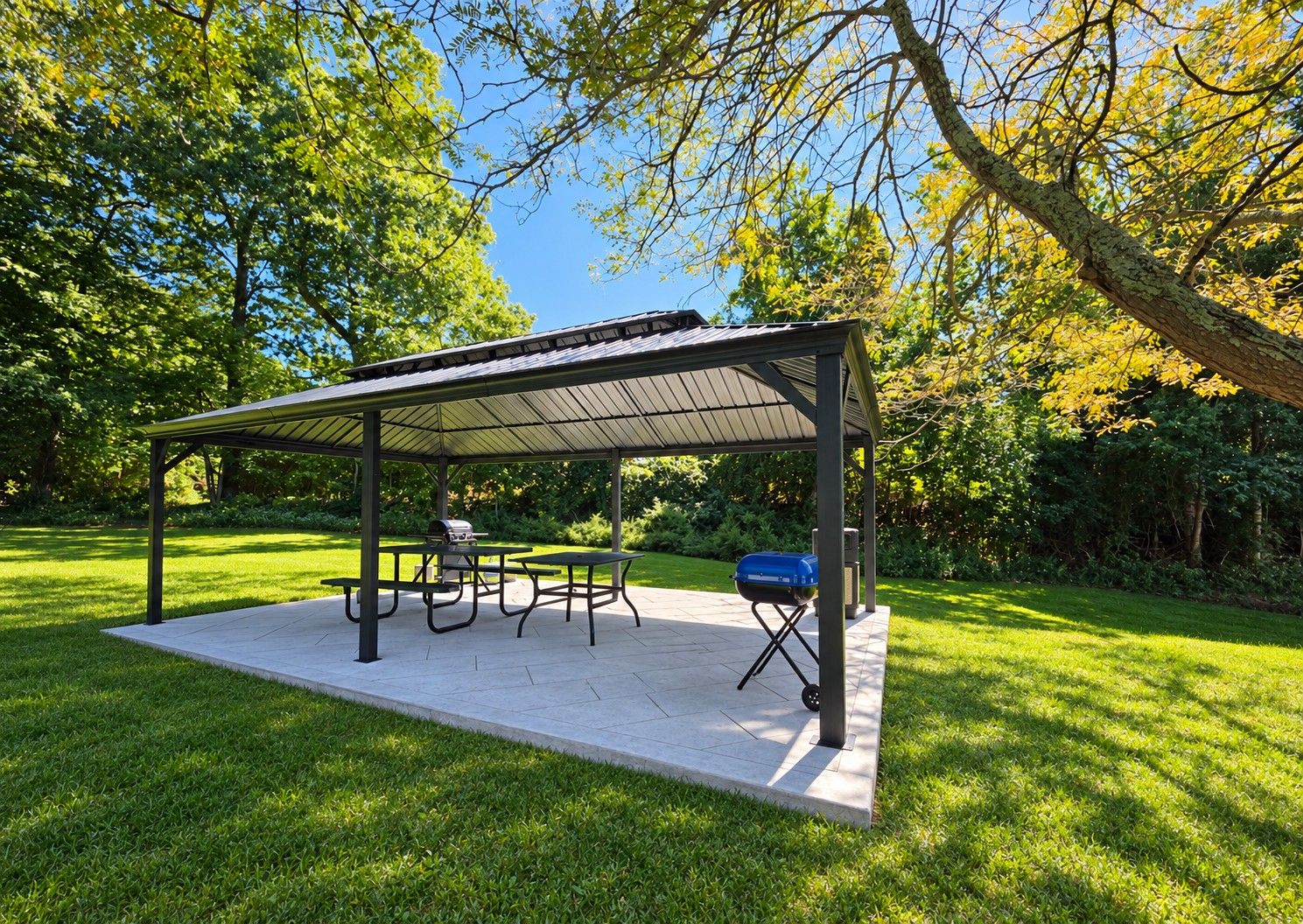 Ett takförsett utomhusområde med sittplatser, picknickbord och en grill.