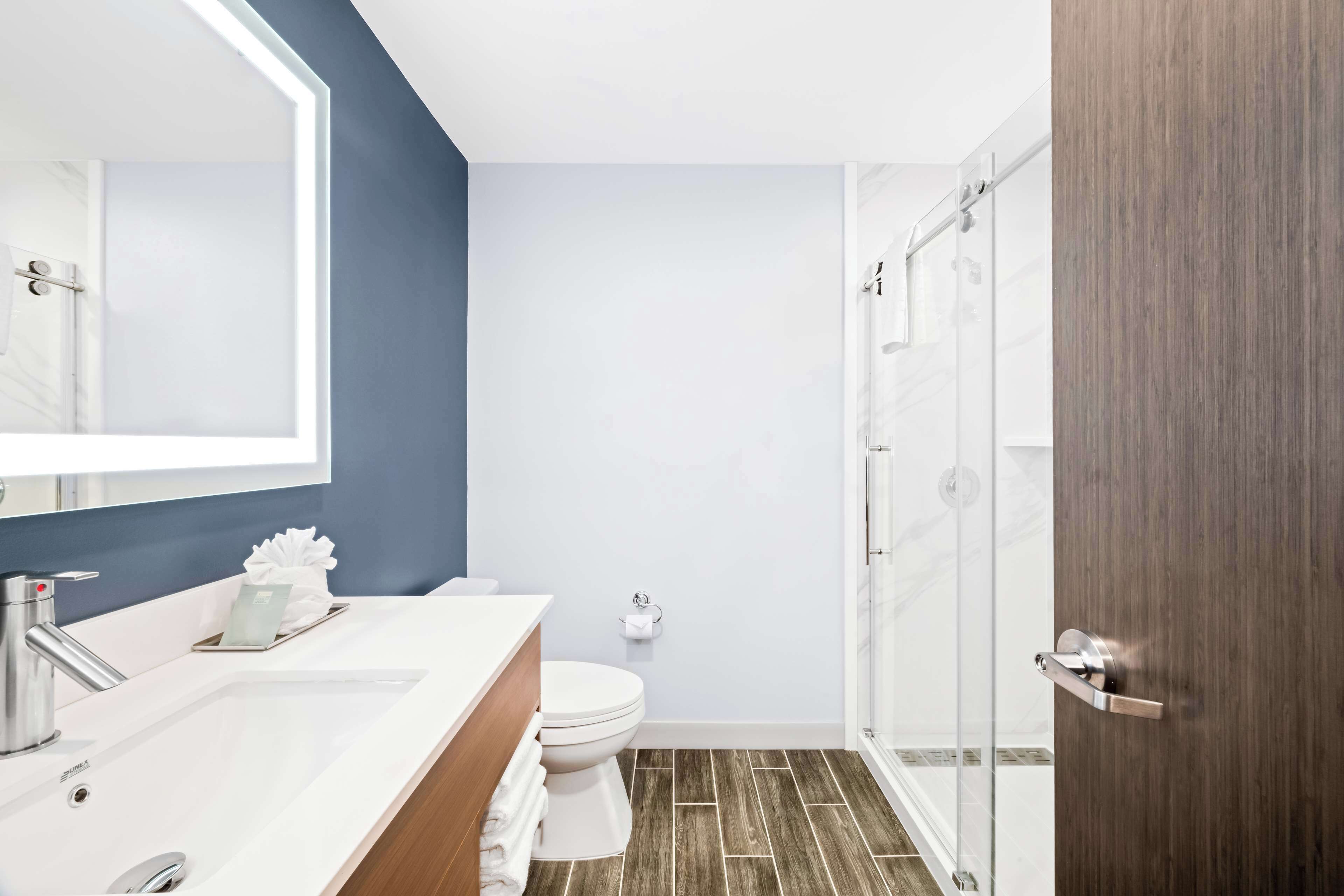 A modern bathroom with a white sink, a toilet, and a shower area.