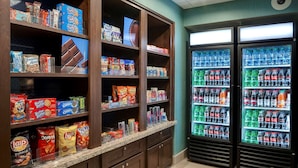 Un área de exhibición de aperitivos y bebidas, con diversas opciones de snacks empaquetados y una selección de bebidas embotelladas.