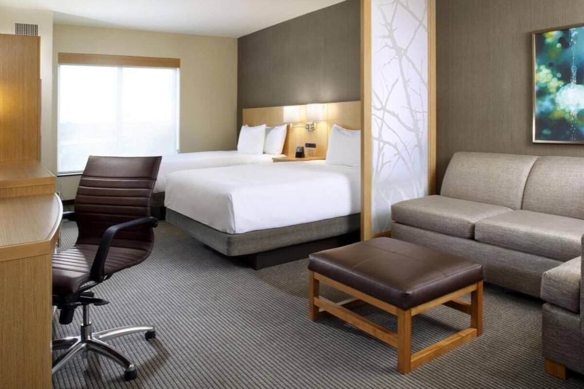 A hotel room with a bed, a sofa, a desk, and a chair.