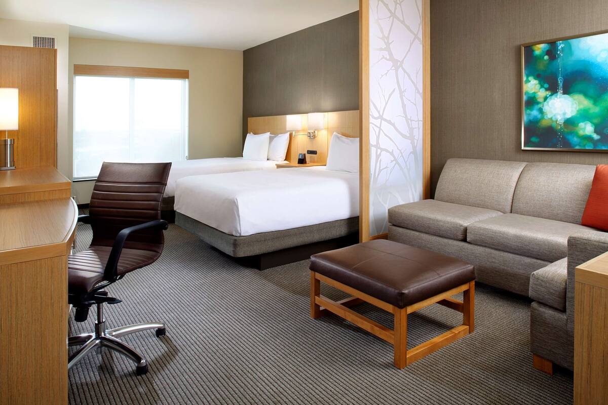 A hotel room with a large bed, a sofa, a desk, and a chair.
