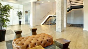 A spacious lobby with a large leather ottoman, a staircase, and a potted plant.