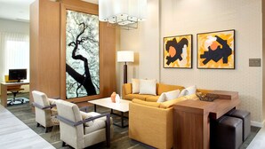 A modern hotel room with a sofa, armchairs, a coffee table, and artwork on the walls.