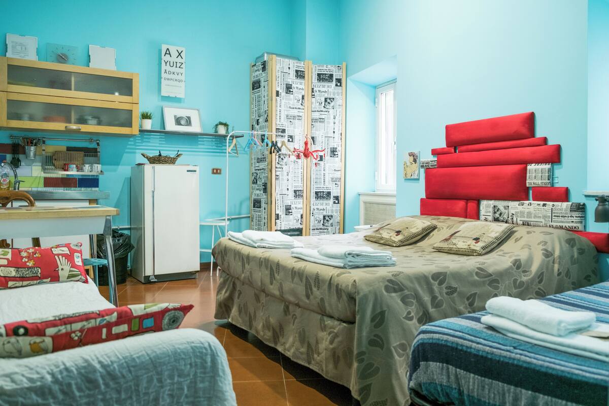 Una habitación con cama, escritorio, refrigerador y armario.