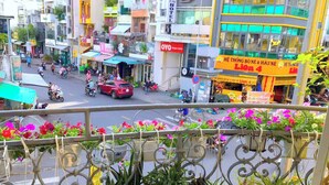Rua movimentada com diversas lojas e um hotel chamado 'Lion 4' ao fundo.