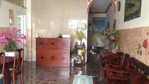A lobby with a wooden bench, a red cabinet, and a small altar with flowers. - Son Tung Hotel (Ho Chi Minh City)