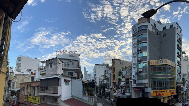 Rua urbana com edifícios, um poste de luz e céu claro.