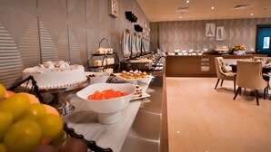 Un bufé con diversos postres y un área de descanso con sillas y una mesa.
