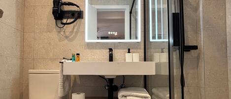 Une salle de bain moderne dotée d’une douche à parois de verre, de toilettes et d’un meuble-lavabo avec un miroir.