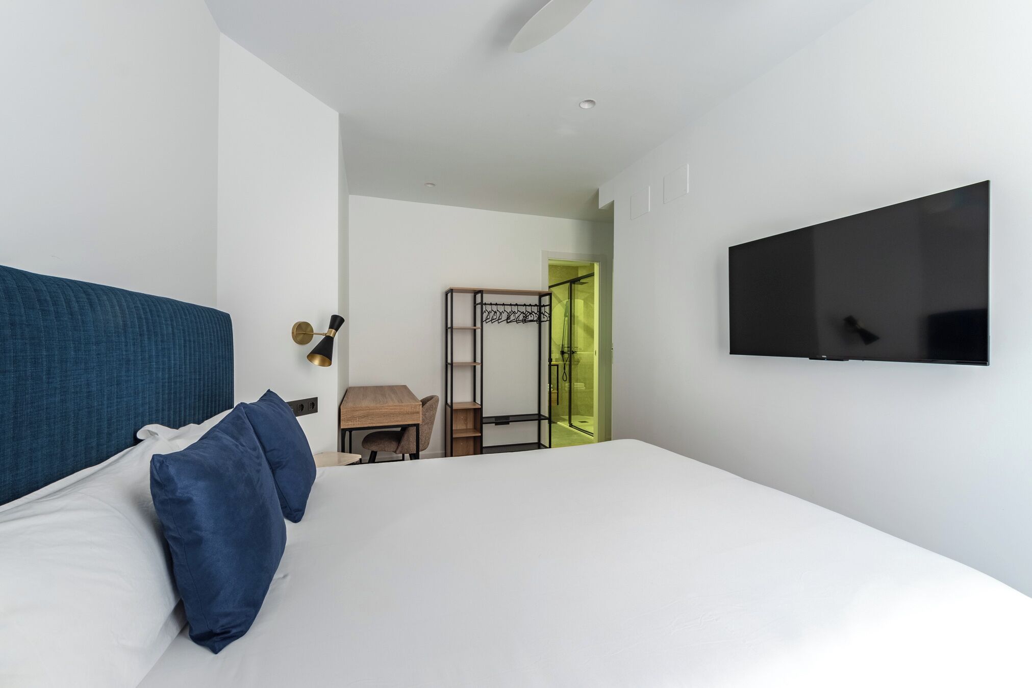 Habitación de hotel con cama, escritorio, silla, televisión y puerta que da a un baño.
