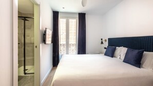 A hotel room with a large bed, a shower area, and a balcony with curtains. -  Arenal Rooms Bilbao (Bilbao)