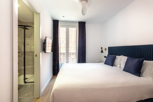 A hotel room with a large bed, a shower area, and a balcony with curtains. -  Arenal Rooms Bilbao (Bilbao)