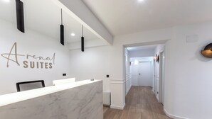 A hotel reception area with a marble counter, black pendant lights, and a sign reading "Arena Suites." -  Arenal Rooms Bilbao (Bilbao)