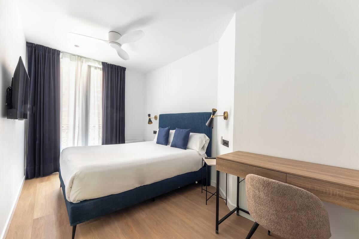 A modern hotel room with a single bed, a desk, and a chair.