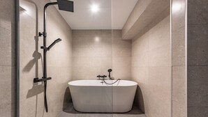 A modern bathroom with a freestanding bathtub, a glass-enclosed shower area, and a tiled floor. -  Arenal Rooms Bilbao (Bilbao)