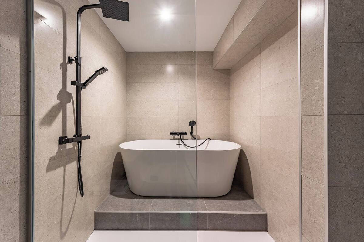 A modern bathroom with a freestanding bathtub, a glass-enclosed shower area, and a tiled floor.