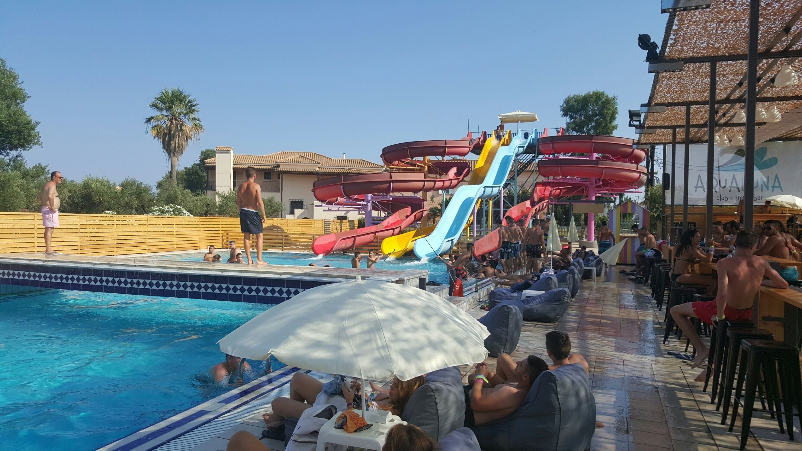 A pool area with multiple water slides and a bar area with umbrellas.