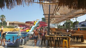 A water park with multiple water slides, a pool area with lounge chairs, and a snack bar.