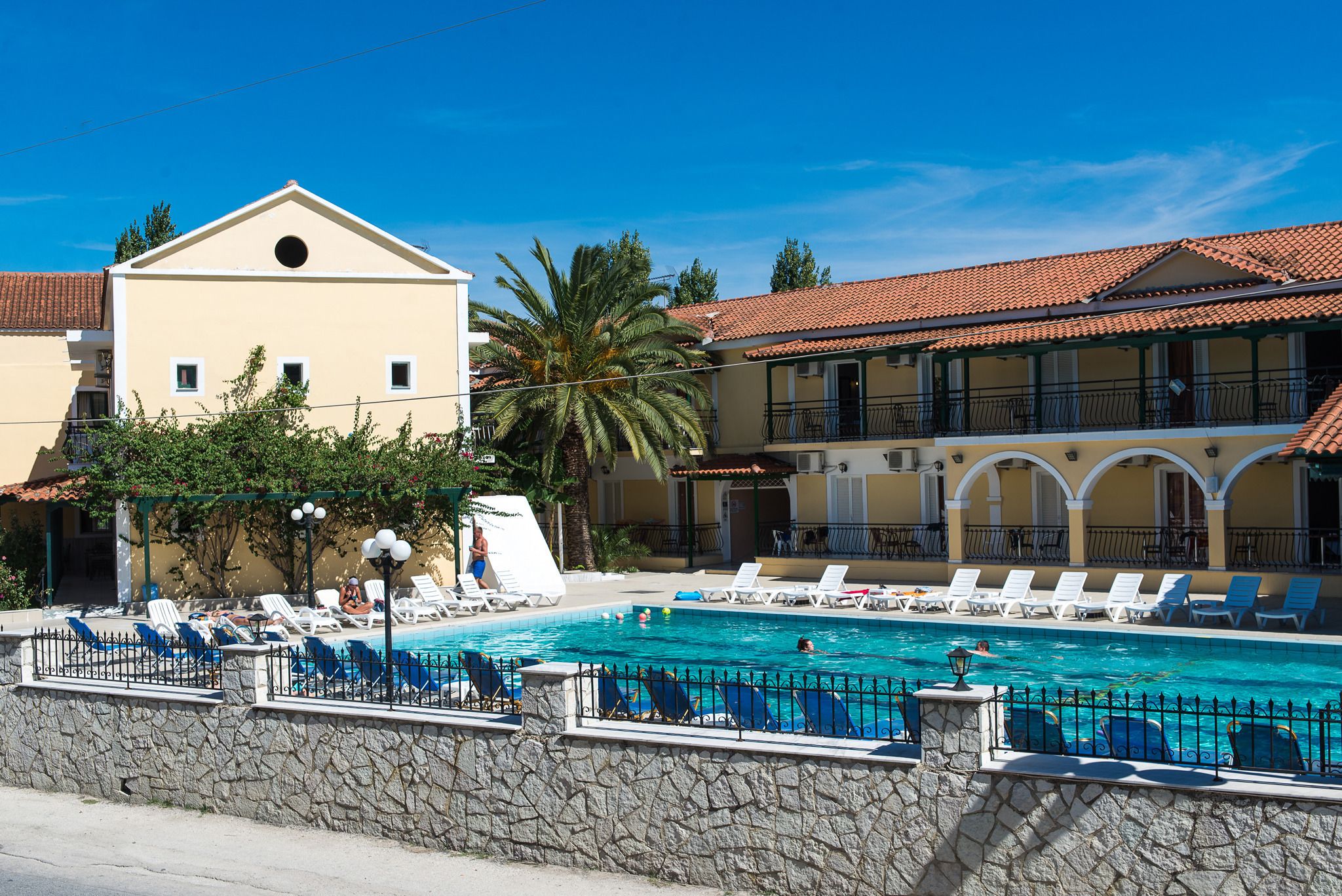 A pool area with lounge chairs and a stone wall.