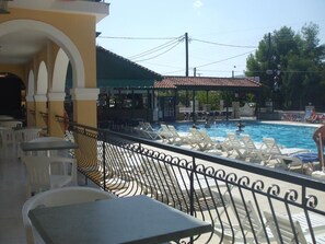 A poolside area with lounge chairs and a bar area. - Perkes Hotel (Zakynthos)