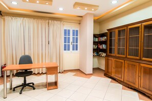 A room with a wooden desk, a chair, a bookshelf, and a window with curtains.