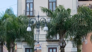 Un edificio con fachada clásica, zona de asientos al aire libre con sombrillas y un cartel que indica atracciones cercanas.