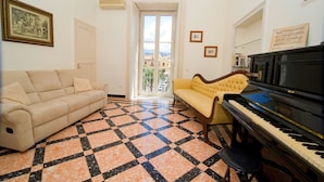 Un salón con un sofá beige, un sofá amarillo, un piano negro y un suelo a cuadros.