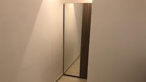 Un pasillo estrecho con un espejo grande que refleja una puerta de madera.