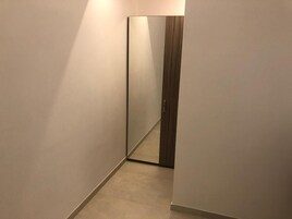 Ein schmaler Flur mit einem großen Spiegel, der eine Holztür widerspiegelt.