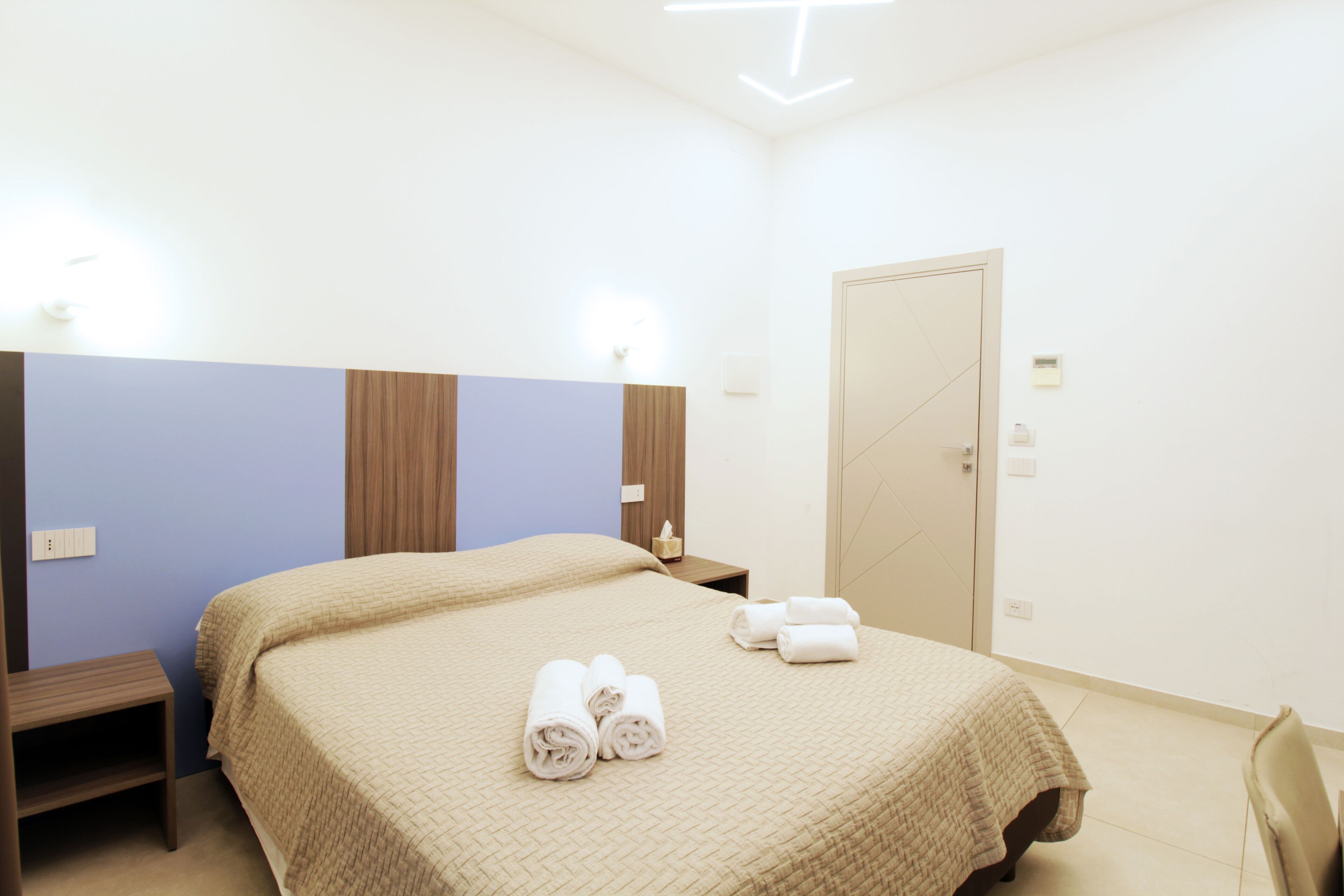 Ein Hotelzimmer mit Bett, Nachttisch, Sessel und Tür.