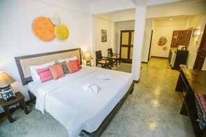 A hotel room with a large bed, a bedside table with a lamp, a chair, and a small table with a vase. - The Odyssey Serviced Apartment (Chiang Mai)