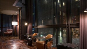 Een modern interieur met lederen fauteuils, een houten vloer en grote ramen.