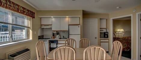 A compact kitchen with a dining area, a ceiling fan, and a window with blinds.