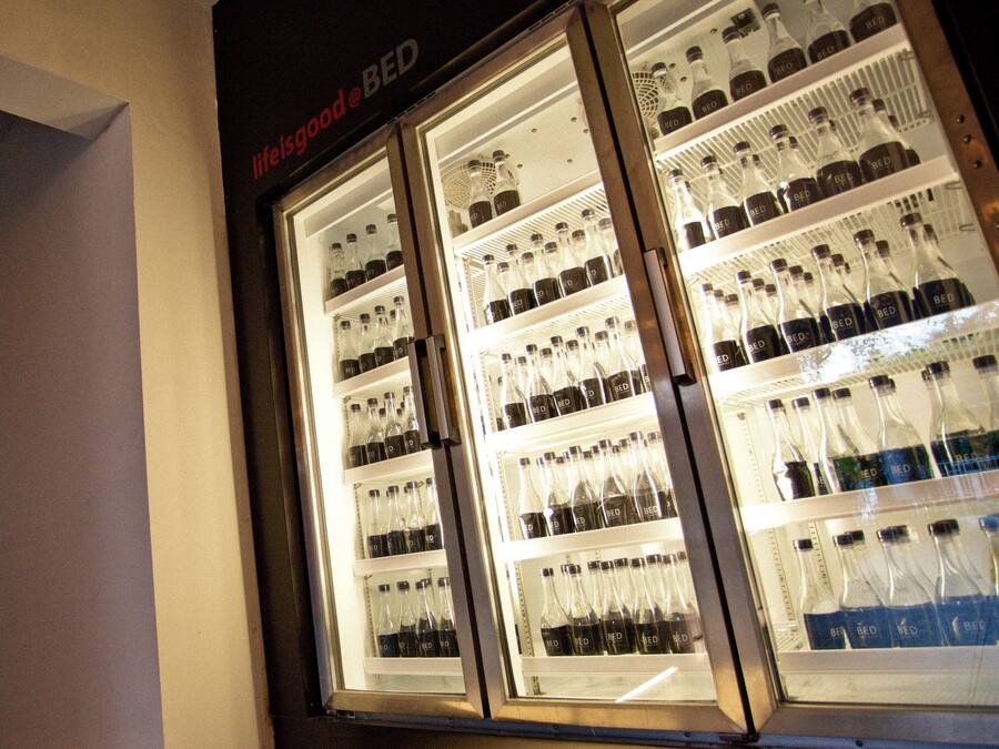 Een gekoelde vitrine met meerdere planken vol met flessen drank.