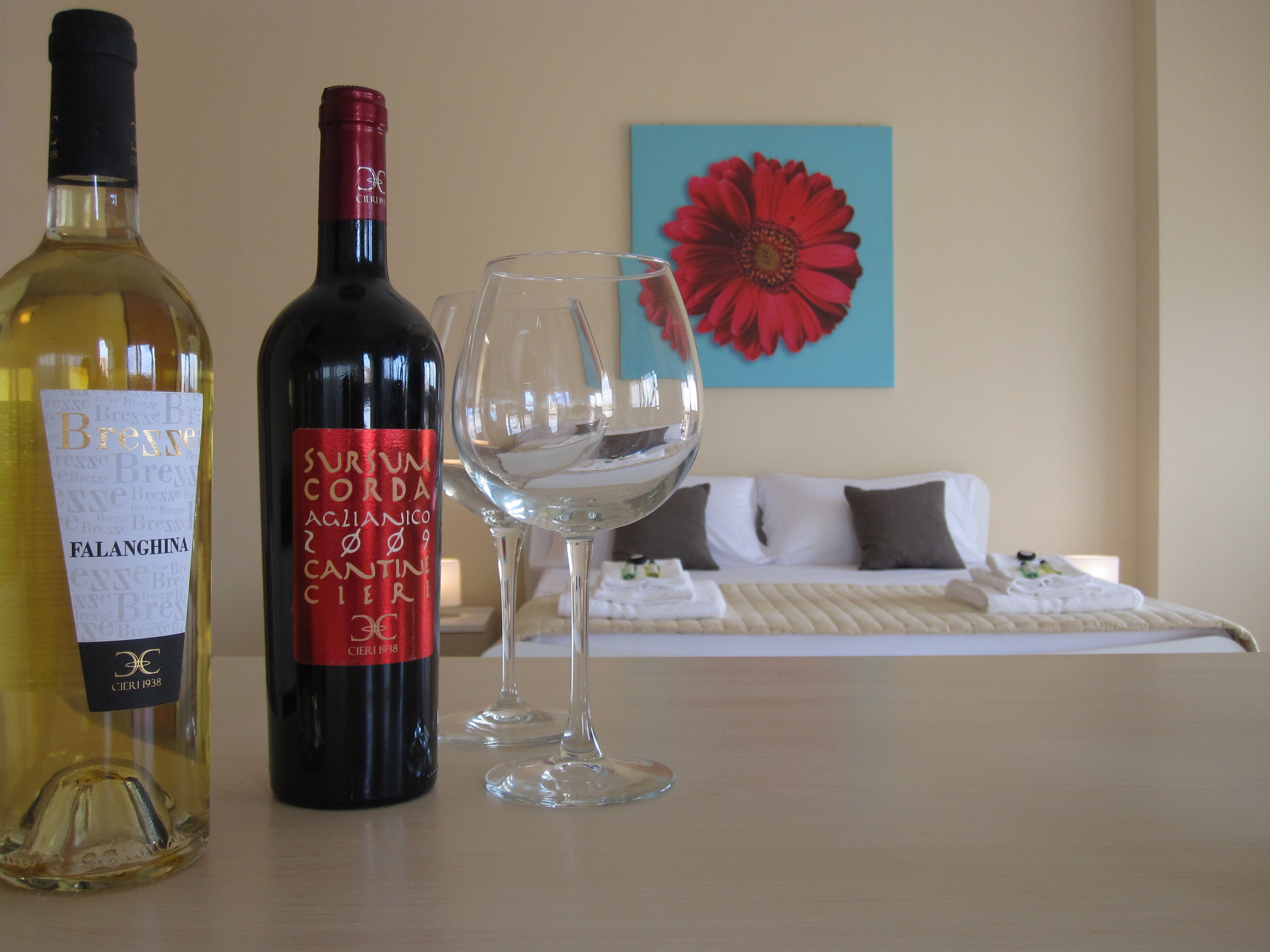 A bottle of Falanghina wine and a bottle of Sauvignon Blanc on a table, with a wine glass in front.
