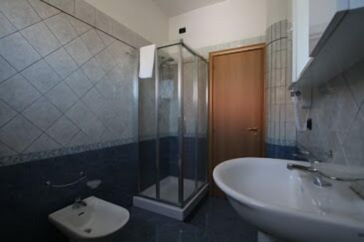 Un baño con cabina de ducha de vidrio, un lavamanos y un inodoro.