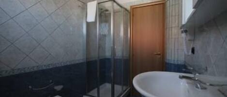 Un baño con cabina de ducha de vidrio, un lavamanos y un inodoro.