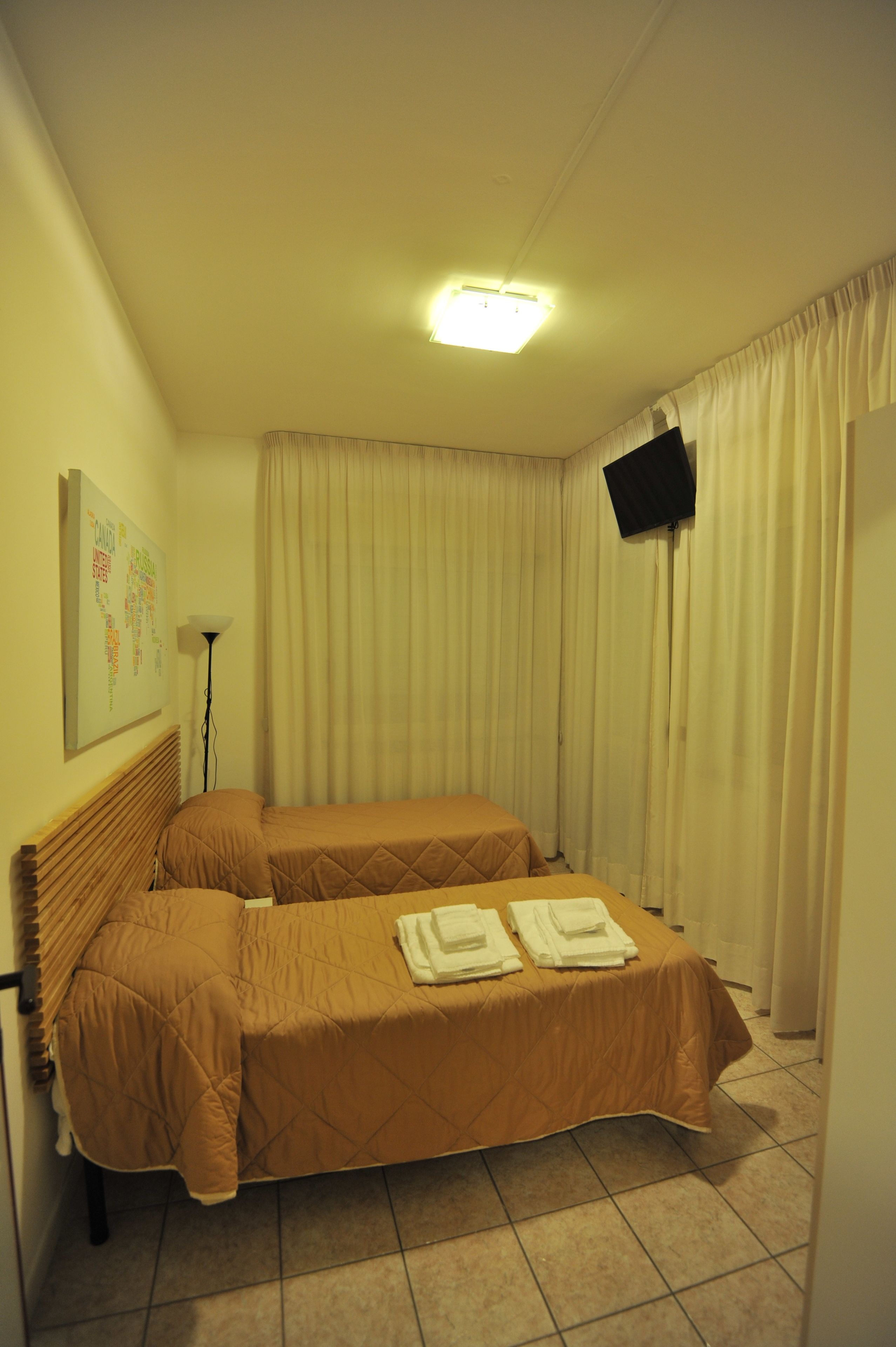 Une chambre d’hôtel avec deux lits, un téléviseur à écran plat, un luminaire au plafond et une carte fixée au mur.