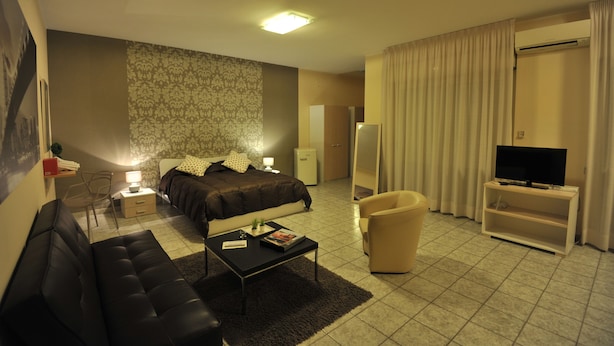 A modern hotel room with a bed, a sofa, a TV stand, a desk, and a mirror. - Quarantadue Quindici (Termoli)