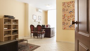 A living room with a sofa, a coffee table, a bookshelf, two chairs, a desk, and a colorful abstract painting on the wall. - Quarantadue Quindici (Termoli)